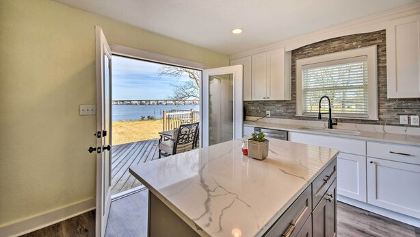 A kitchen with a large island, white cabinets, and a view of the beach. - Portsmouth Waterfront Vacation Rental w/ Deck (Portsmouth)