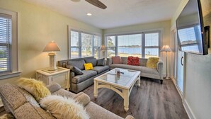 A living room with two sofas, a coffee table, a ceiling fan, and large windows. - Portsmouth Waterfront Vacation Rental w/ Deck (Portsmouth)