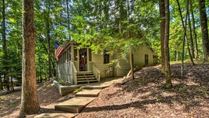 Une cabane dotée d’une véranda, d’un escalier en bois et offrant une vue sur la forêt.
