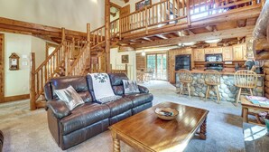 A spacious living area with a leather sofa, wooden coffee table, and a staircase leading to an upper level.