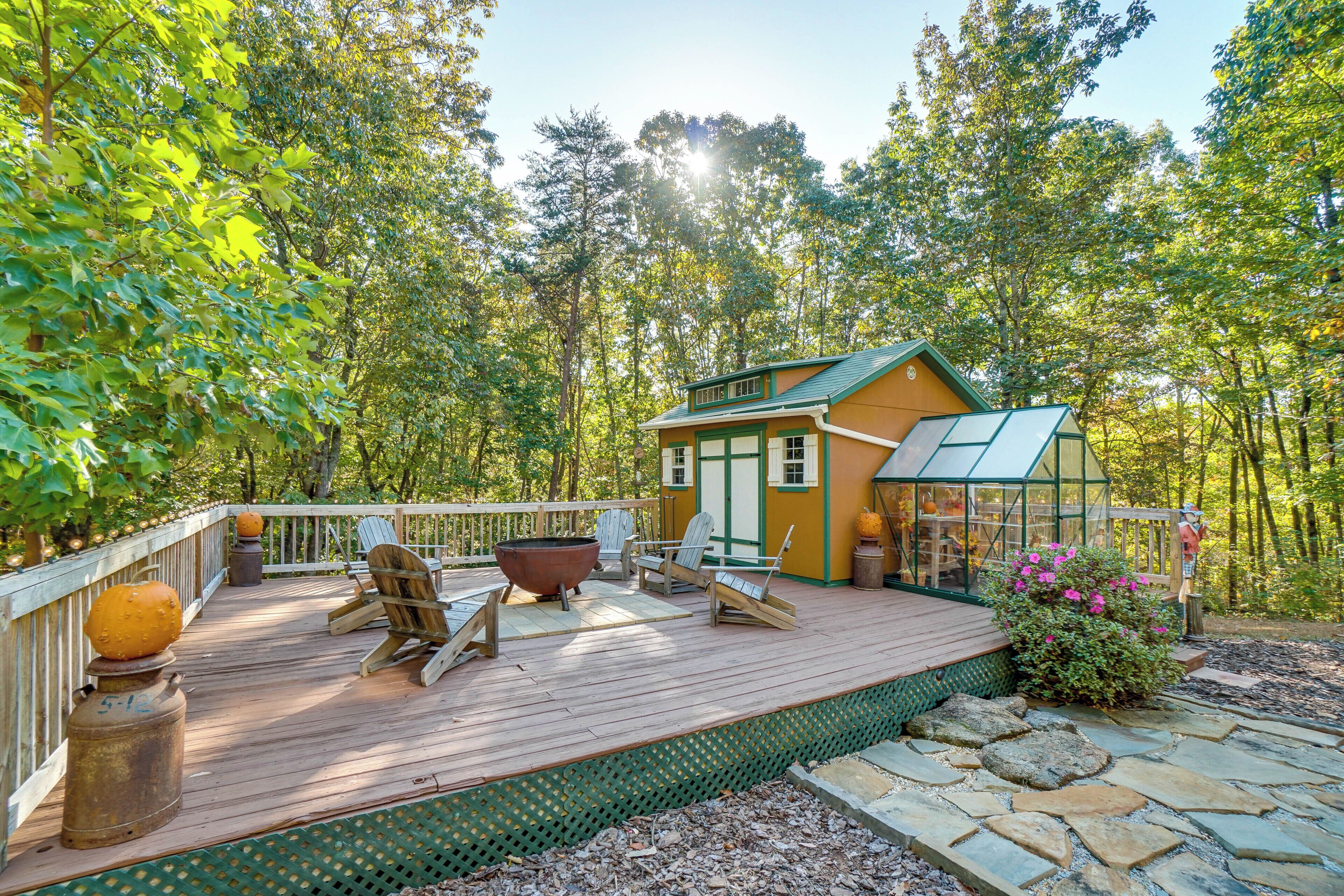 Un patio in legno con poltrone Adirondack, un braciere e una serra in vetro.
