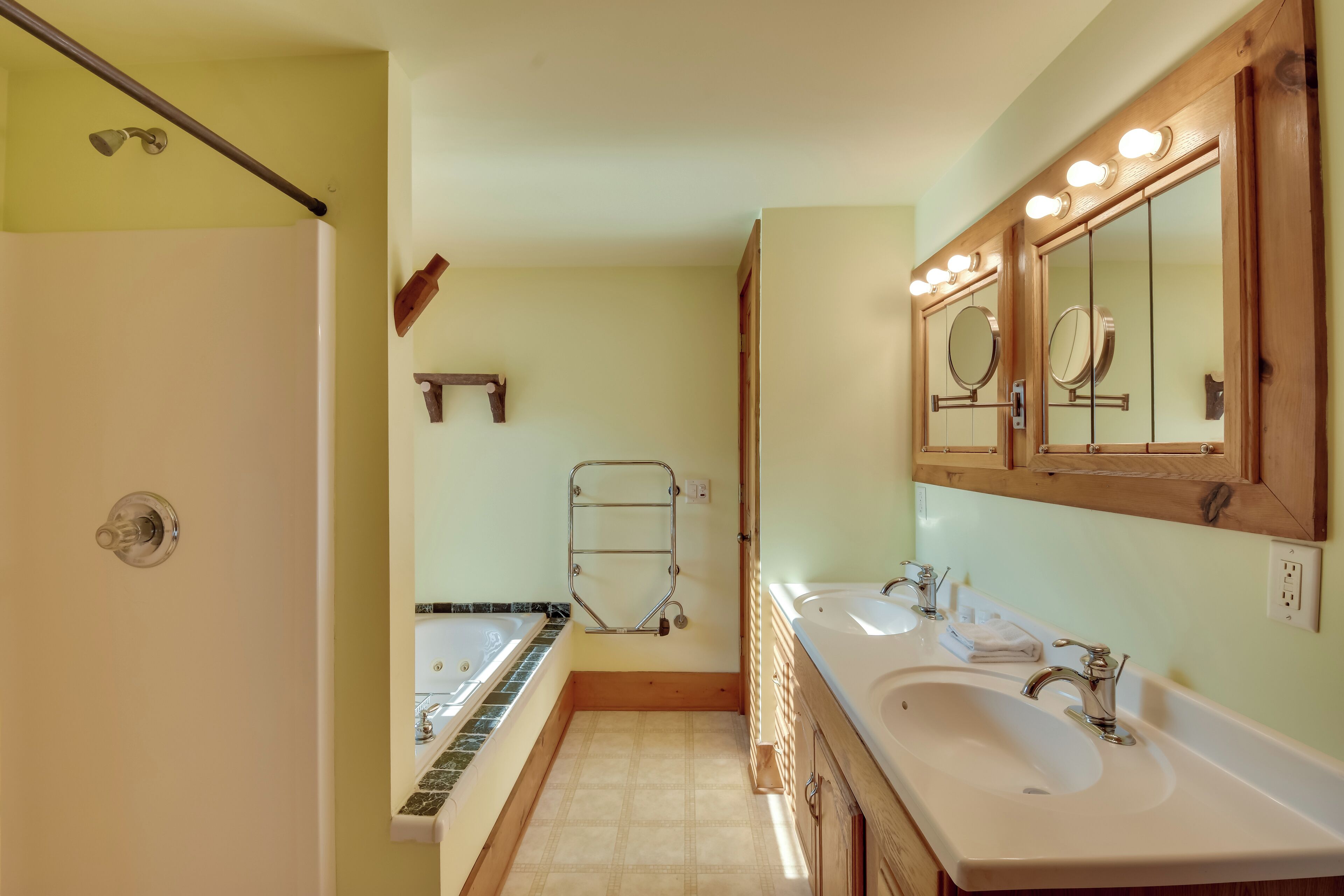 A bathroom with two sinks, a bathtub, and a shower.