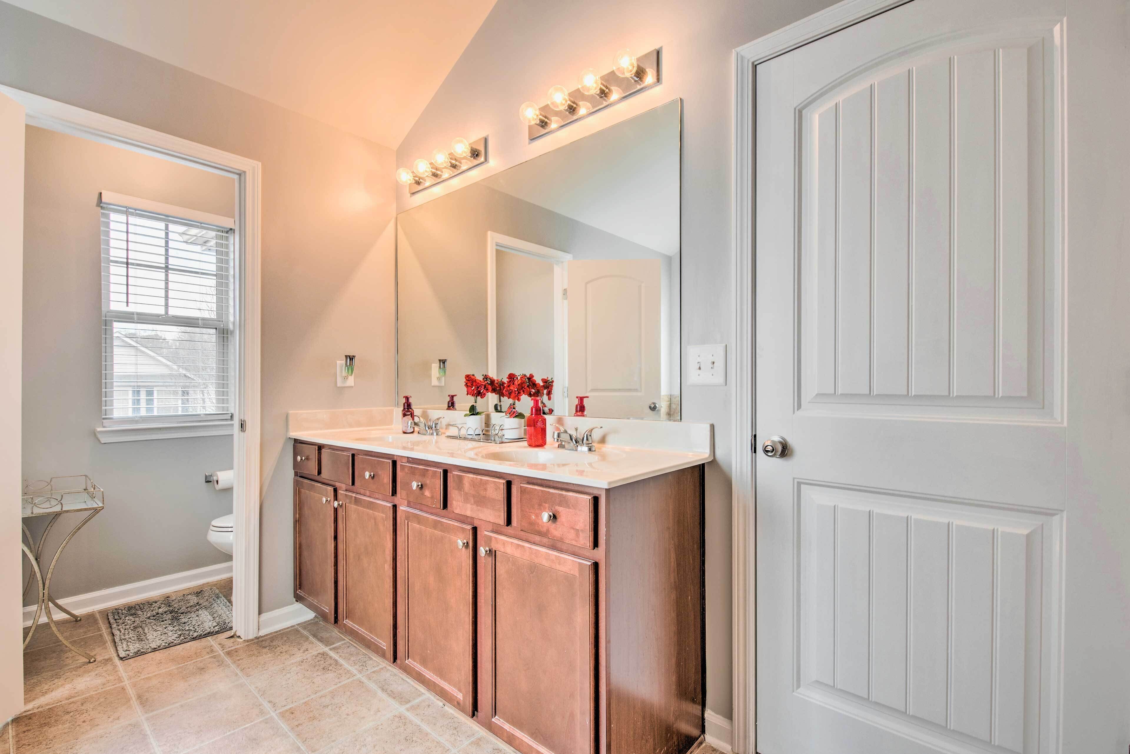 A bathroom with a vanity, a large mirror, and a door.
