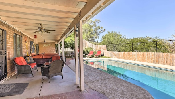 Un patio couvert avec une piscine, du mobilier d’extérieur et une clôture en bois.