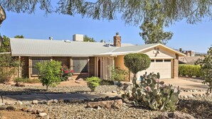 Une maison de plain-pied avec un garage, entourée d’un jardin aménagé avec des cactus et des arbustes.