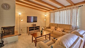 Una sala de estar con sofá, mesa de centro, chimenea, televisor y lámparas decorativas.