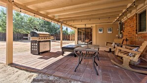 Un patio al aire libre con una parrilla, zona de estar y suelo de ladrillo.