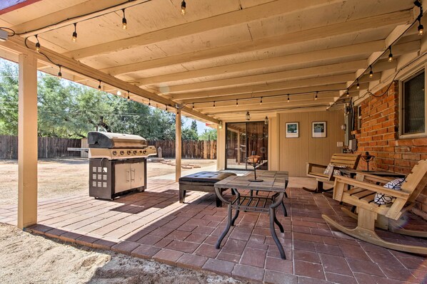 An outdoor patio with a grill, seating area, and brick flooring.