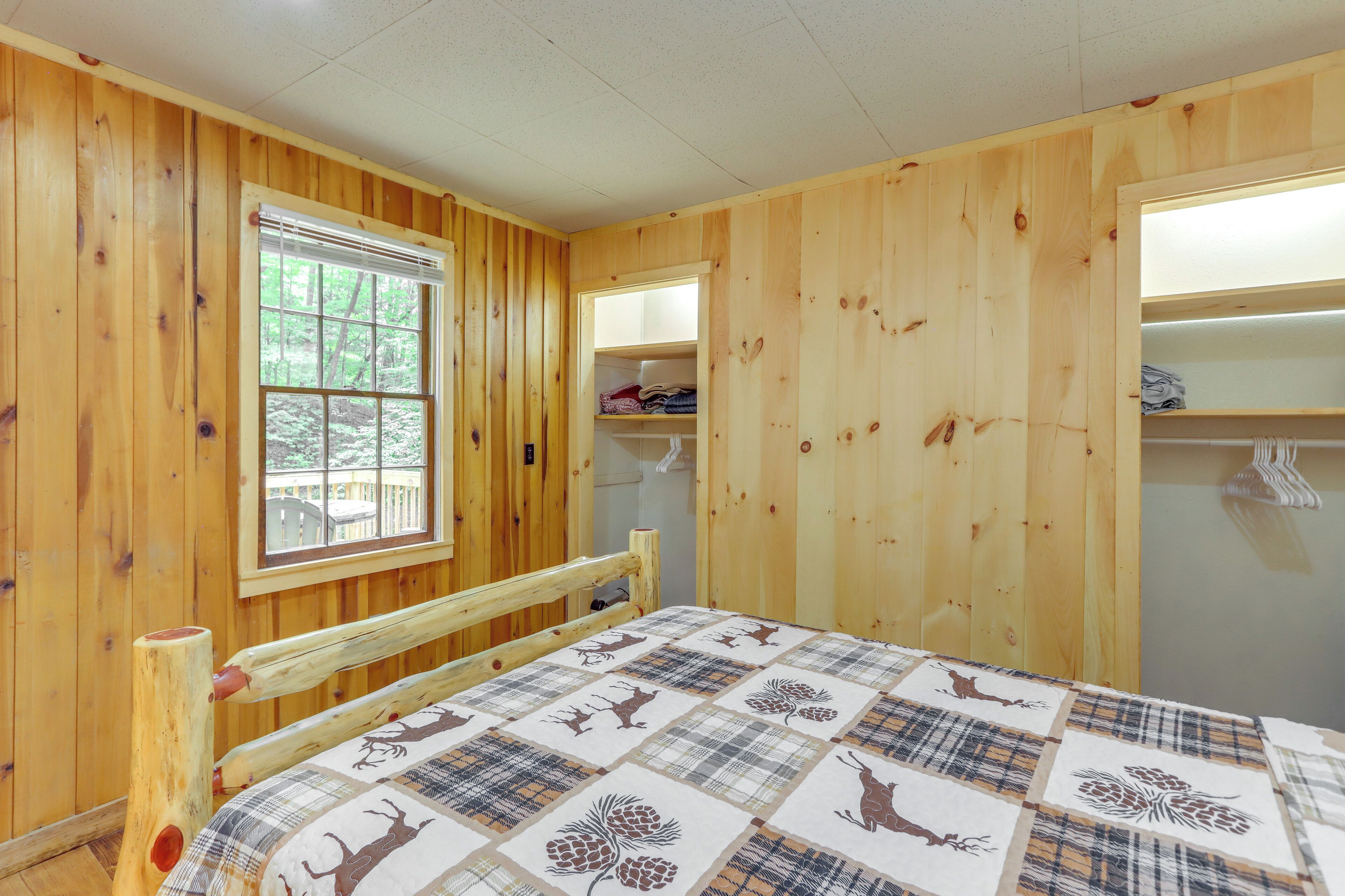 Un dormitorio de cabaña de madera con una cama, una ventana y un armario de madera.