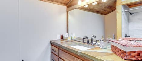 Une salle de bain avec un plafond en bois, un grand miroir, un lavabo et un porte-serviettes.