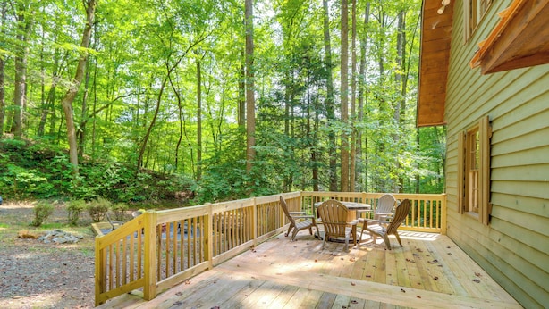 A wooden deck with a table and chairs, surrounded by a forested area. - Wooded Blue Ridge Cabin: 2 Decks, Fire Pit! (Cherry Log)