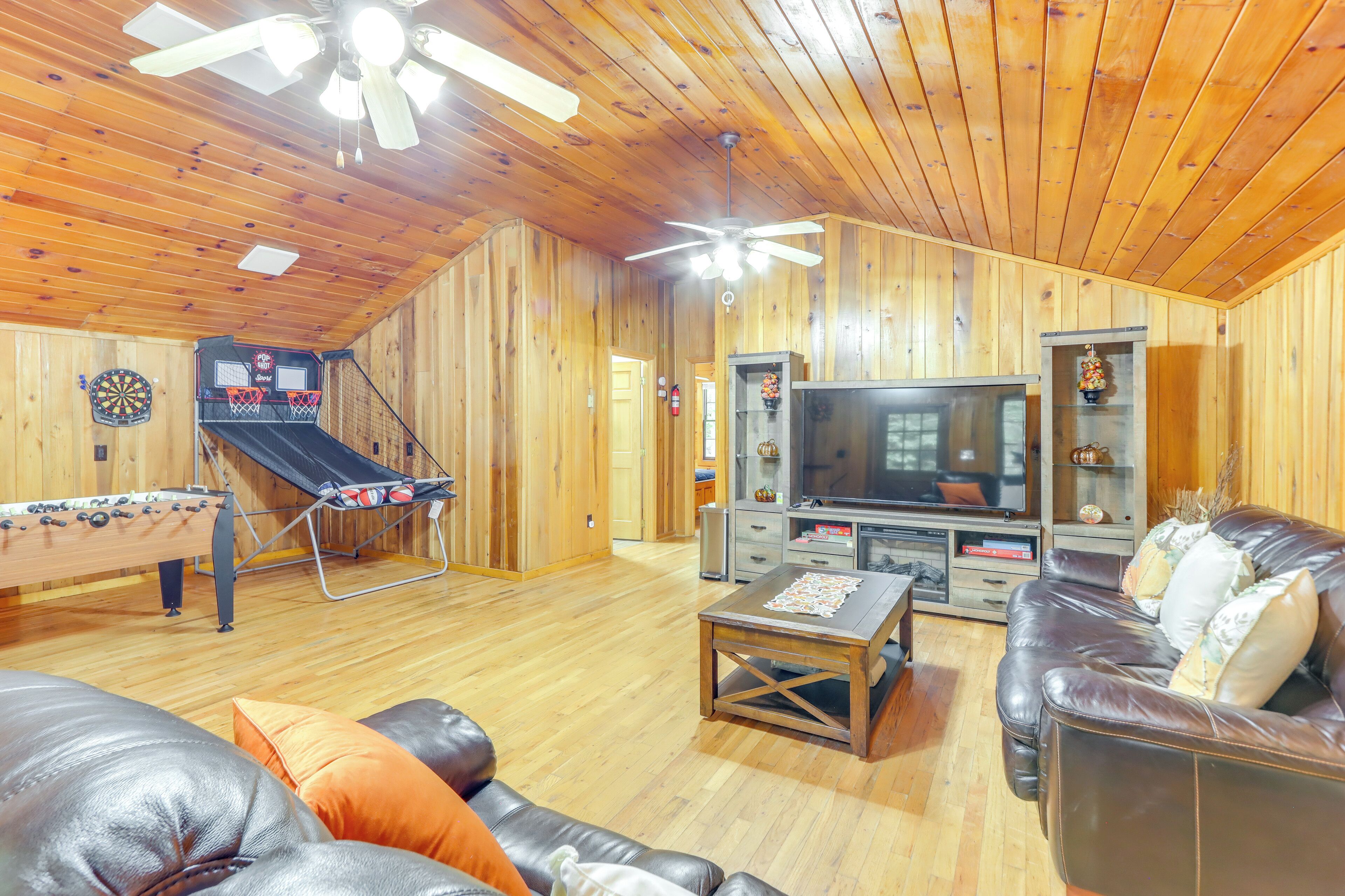 Ein Zimmer mit Holzwandverkleidung, einem Tischtennisplatten, einer Ledersofa und einem Flachbildfernseher.