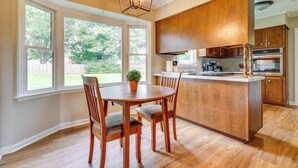 A kitchen with wooden cabinets, a central island, and a dining area with chairs. - Decatur Vacation Rental w/ Patio! (Decatur)
