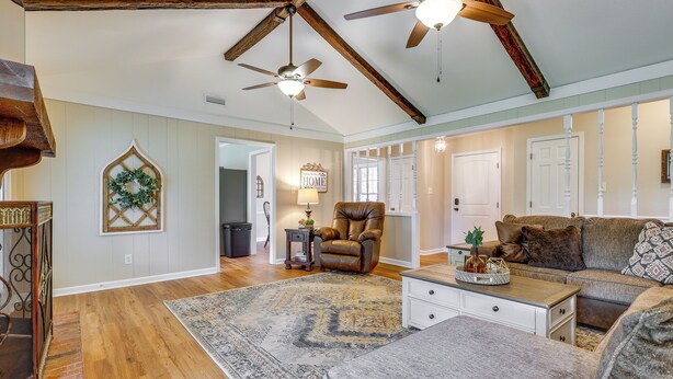 A spacious living room with hardwood floors, a large sectional sofa, a fireplace, and a ceiling fan. - Decatur Vacation Rental w/ Patio! (Decatur)