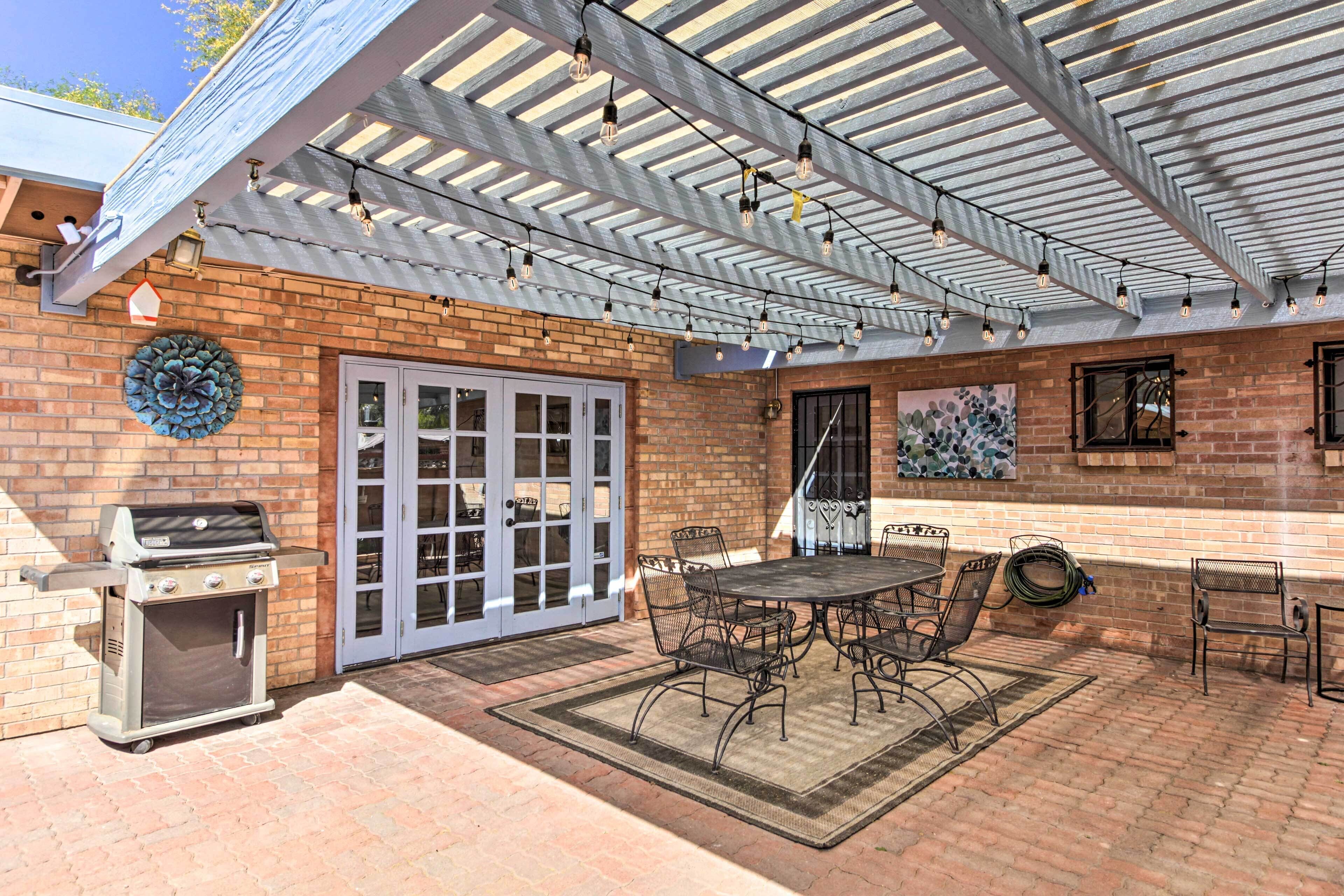 A covered patio with a grill, dining table, and chairs.