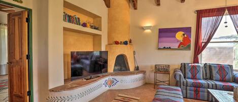 Una sala de estar acogedora con chimenea de piedra, un sofá y una televisión.