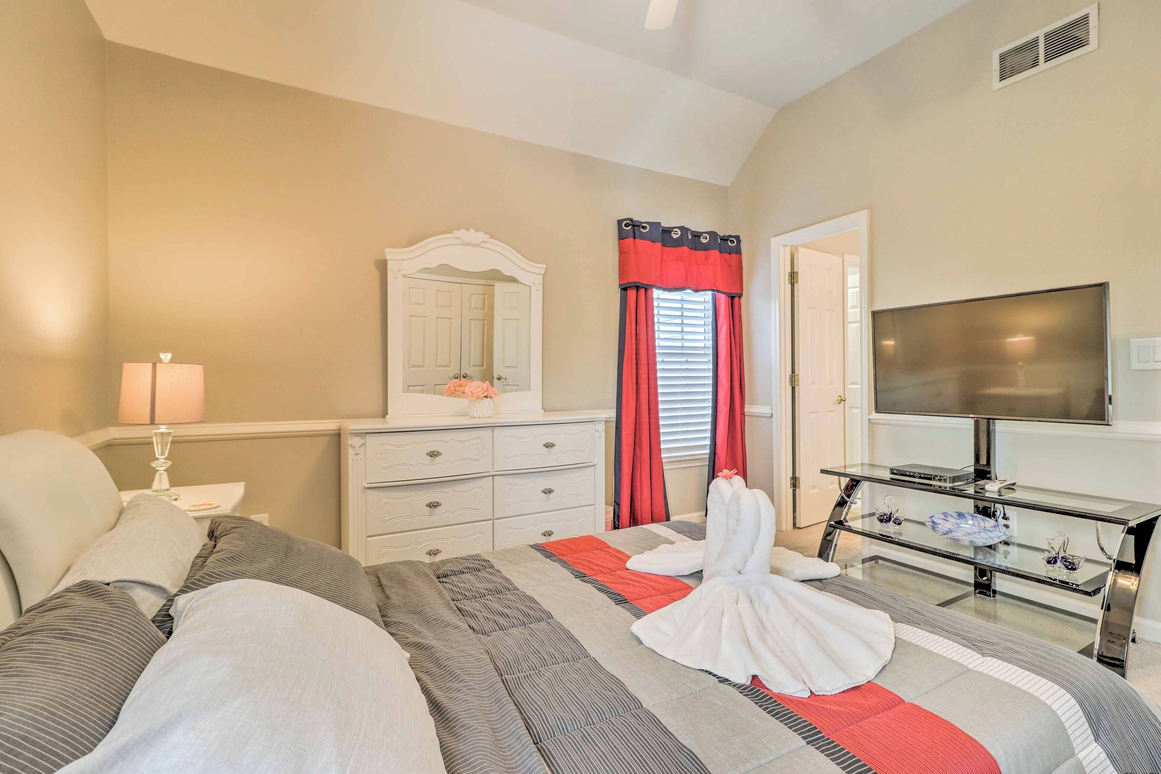 A hotel room with a bed, a TV, a dresser, and a mirror.