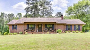 A two-story brick house with a front porch, a chimney, and a well-maintained lawn. - Cozy Georgia Getaway w/ Deck, Grill & Fire Pit! (Cartersville)