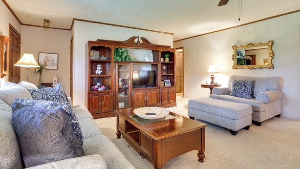 A living room with a sofa, ottoman, wooden coffee table, and a cabinet with glass doors. - Cozy Georgia Getaway w/ Deck, Grill & Fire Pit! (Cartersville)