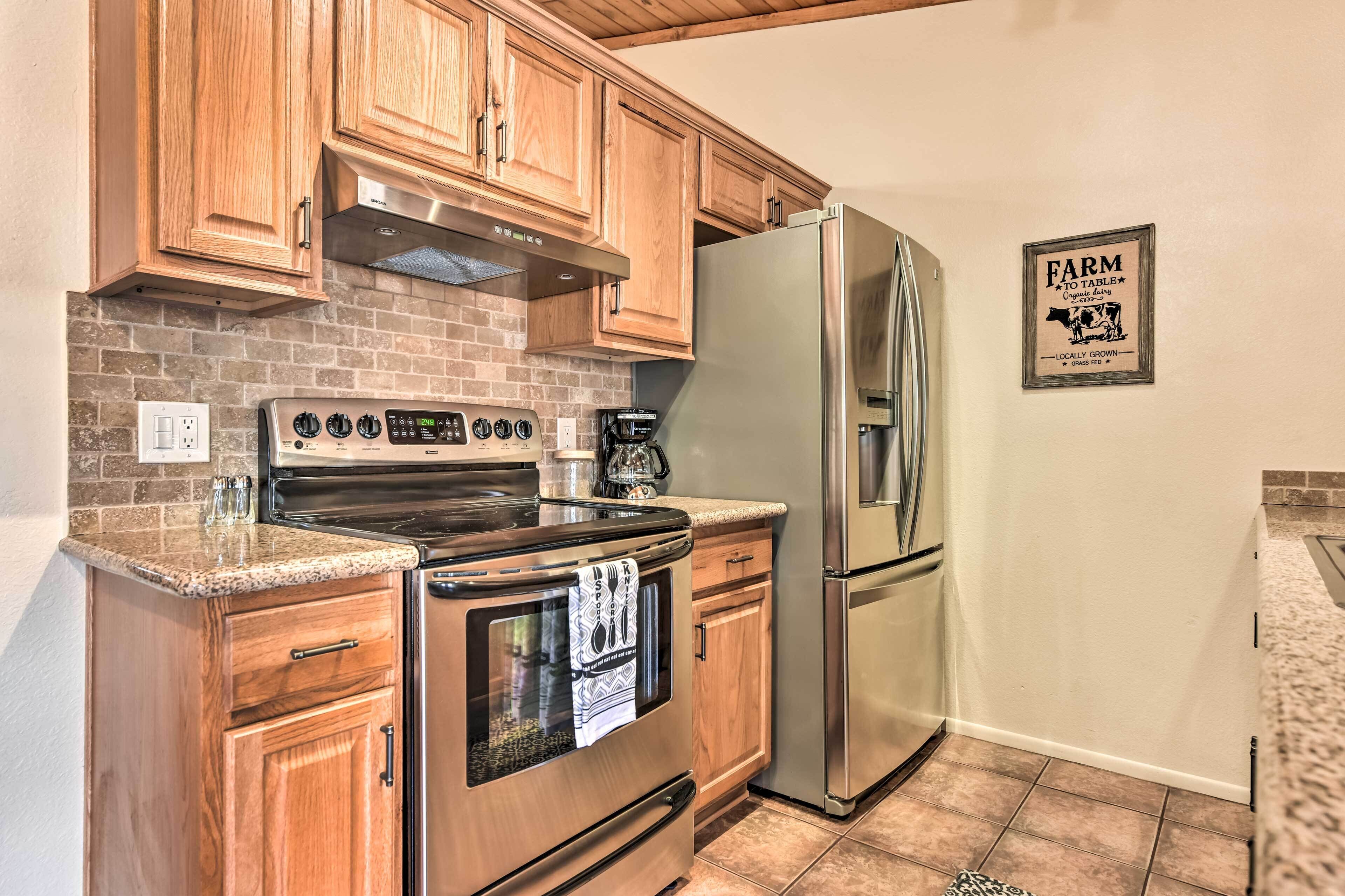 A kitchen with wooden cabinets, a stainless steel refrigerator, and a brick backsplash.