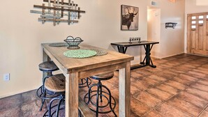A kitchen with wooden bar stools, a wooden table, and a hanging light fixture. - Fenced Yard & Grill! Tucson Family Escape (Tucson)
