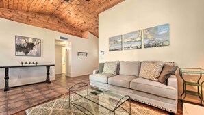 A living room with a wooden ceiling, a sofa, a glass coffee table, and artwork on the walls. - Fenced Yard & Grill! Tucson Family Escape (Tucson)