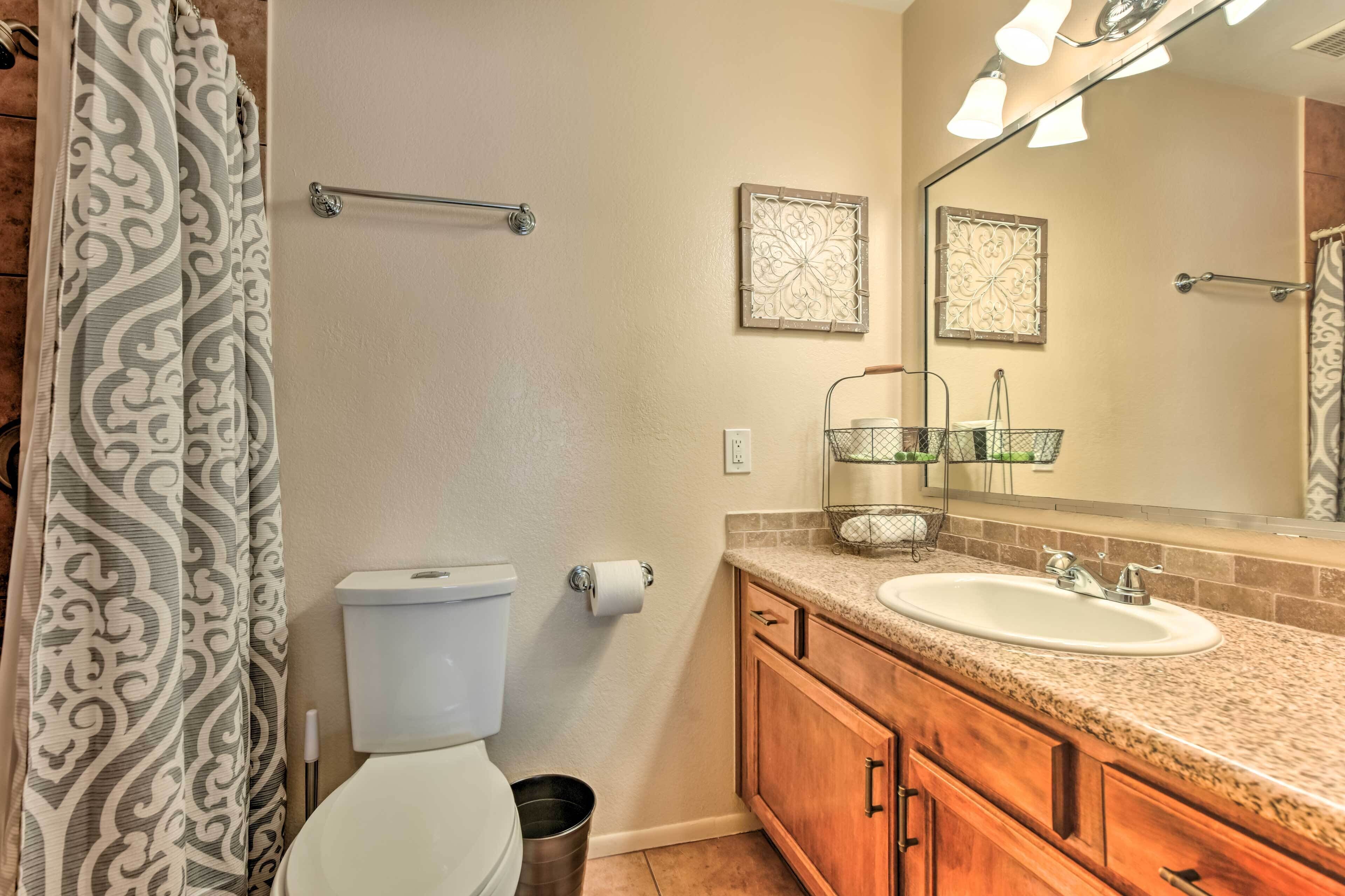 A bathroom with a toilet, sink, vanity, and a shower curtain.