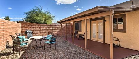 A patio with a table and chairs, a barbecue grill, and a covered area with a door.