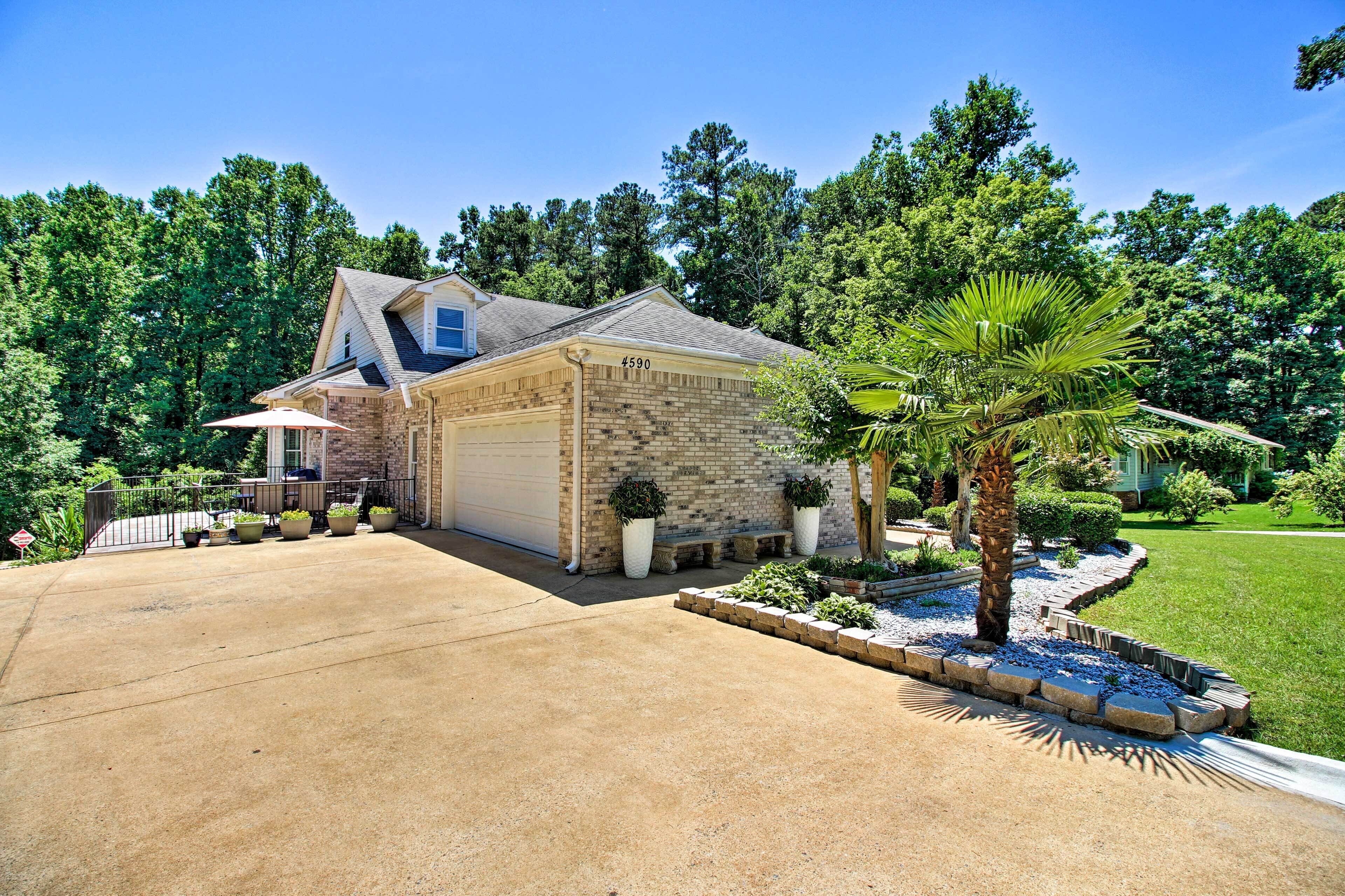 A two-story house with a garage, surrounded by a well-maintained lawn and various potted plants.