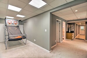 A hallway with a basketball hoop, carpeted floors, and a door leading to another room.