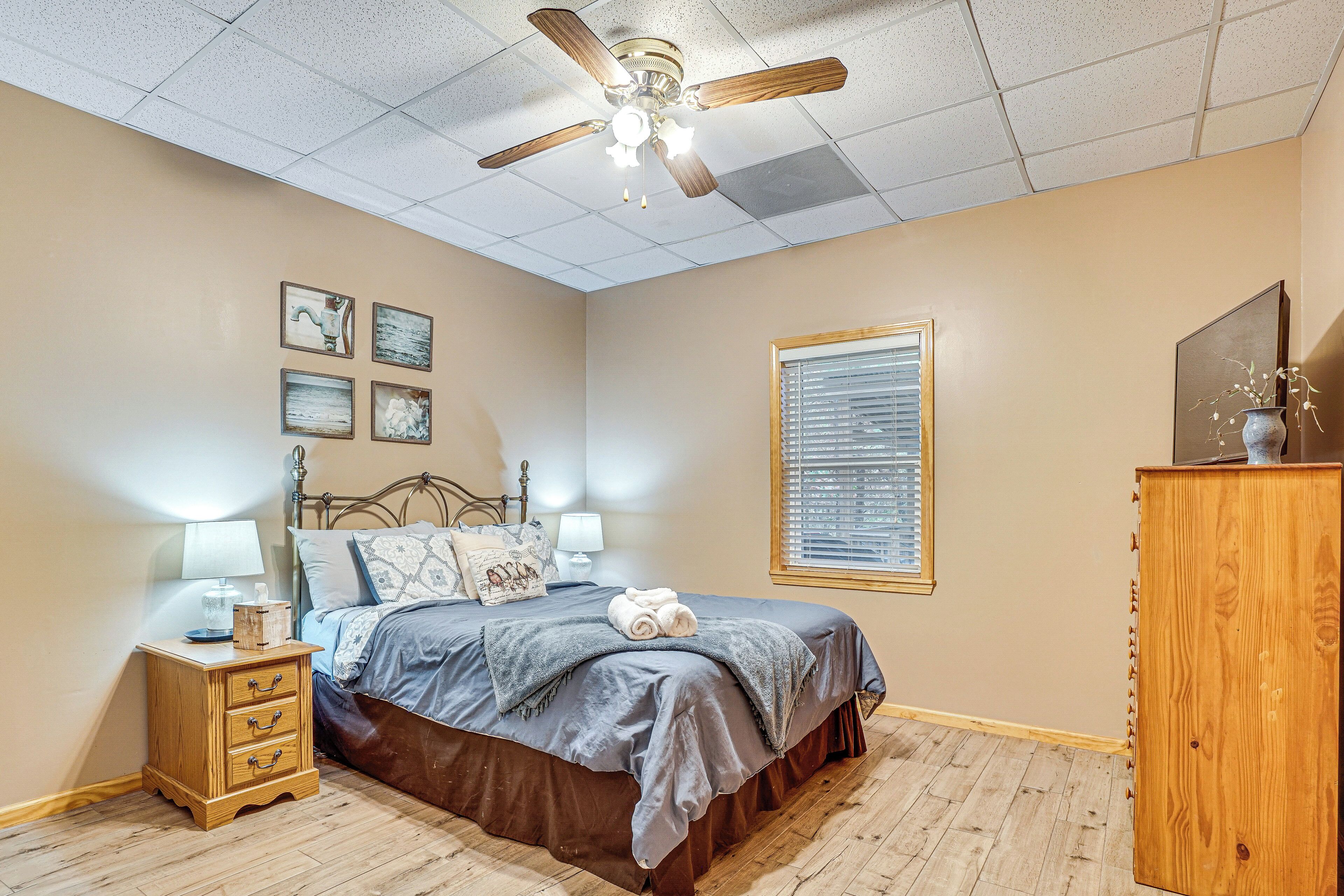A bedroom with a bed, nightstands, a ceiling fan, and a window.