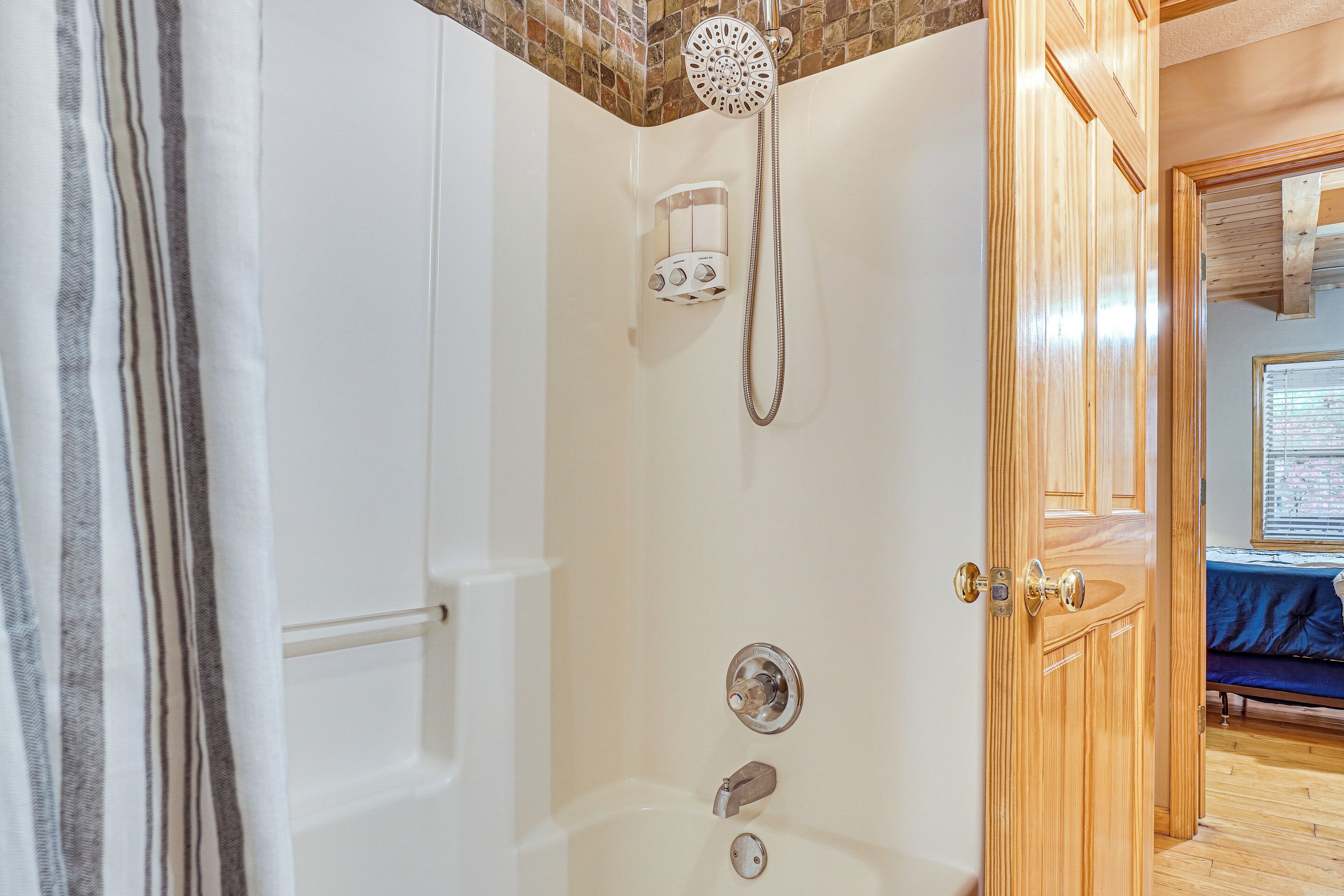 A shower with a handheld showerhead and a wall-mounted control panel.
