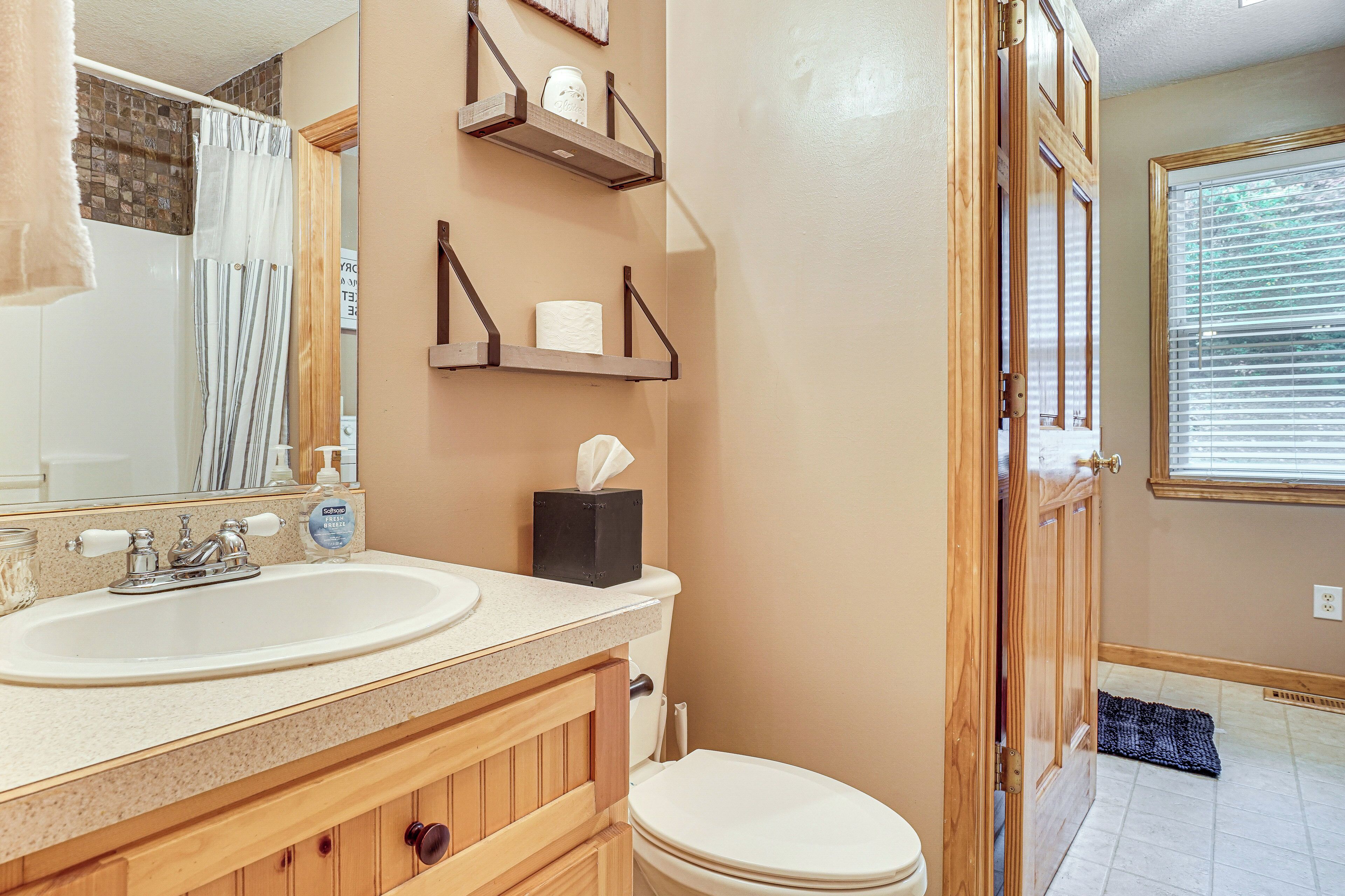 Un baño con tocador de madera, dos lavamanos, inodoro y cortina de ducha.