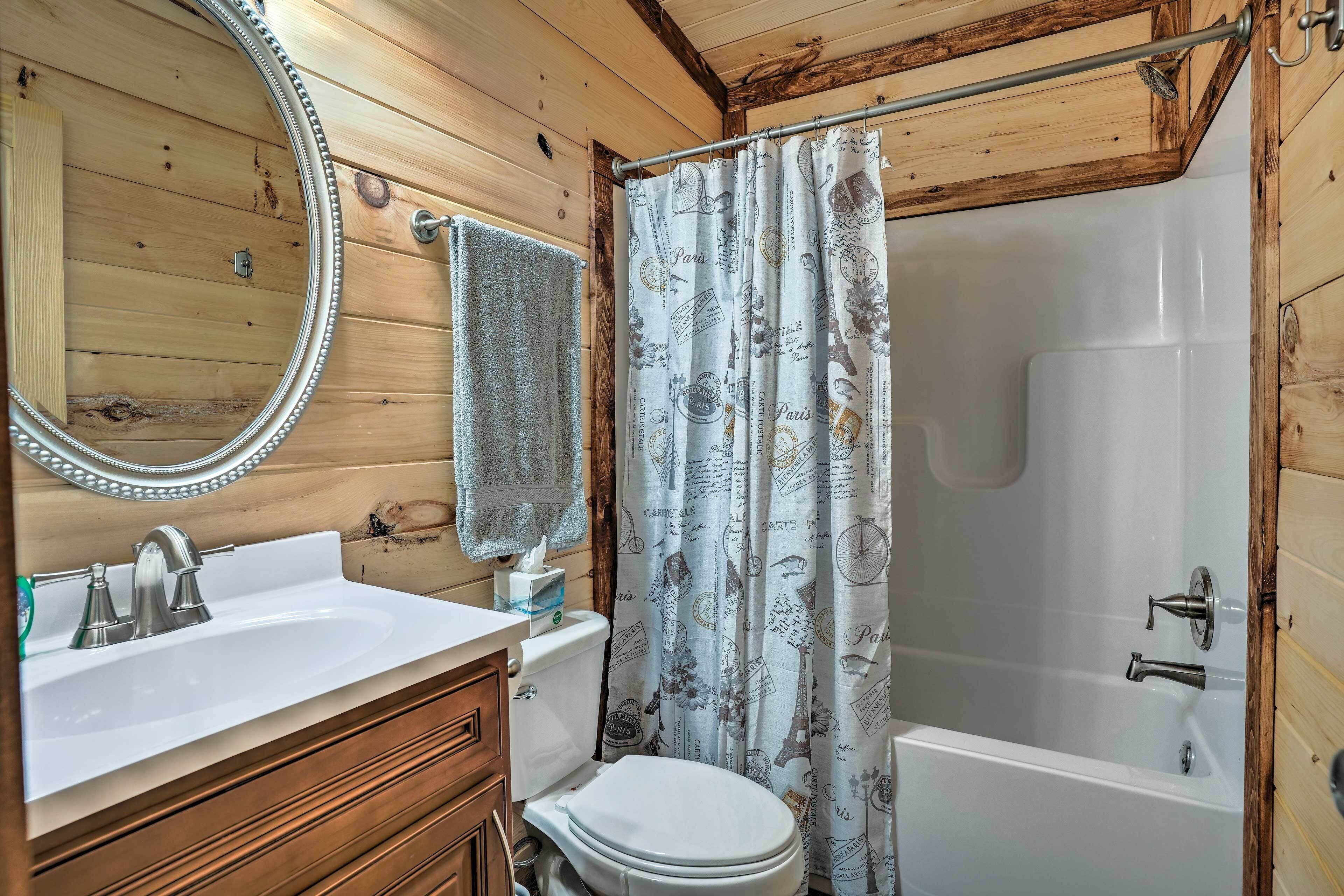 Une salle de bain rustique, avec des murs en bois, comprenant un lavabo blanc, des toilettes et une baignoire.