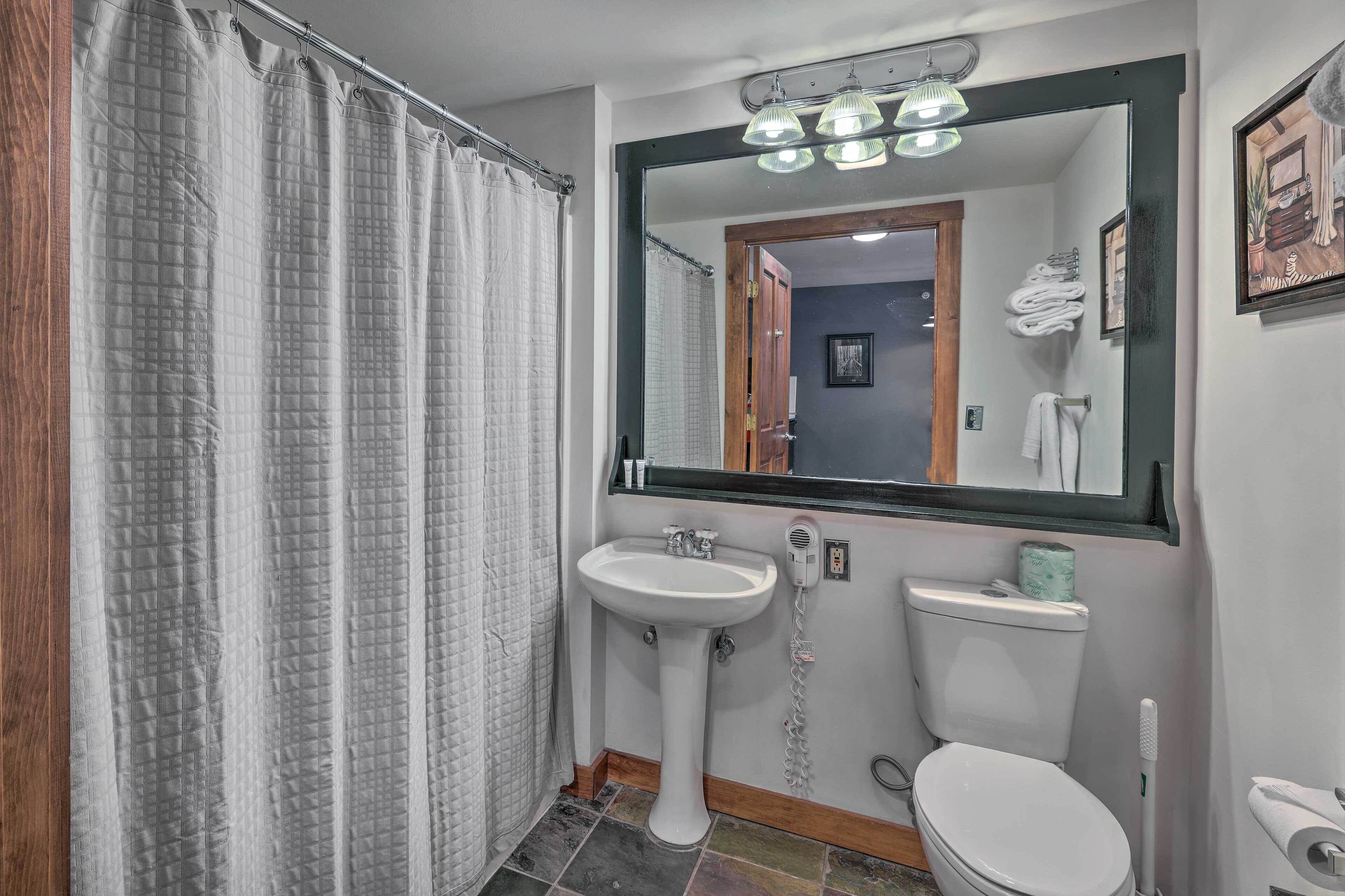 A bathroom with a shower curtain, a sink, a toilet, and a mirror.