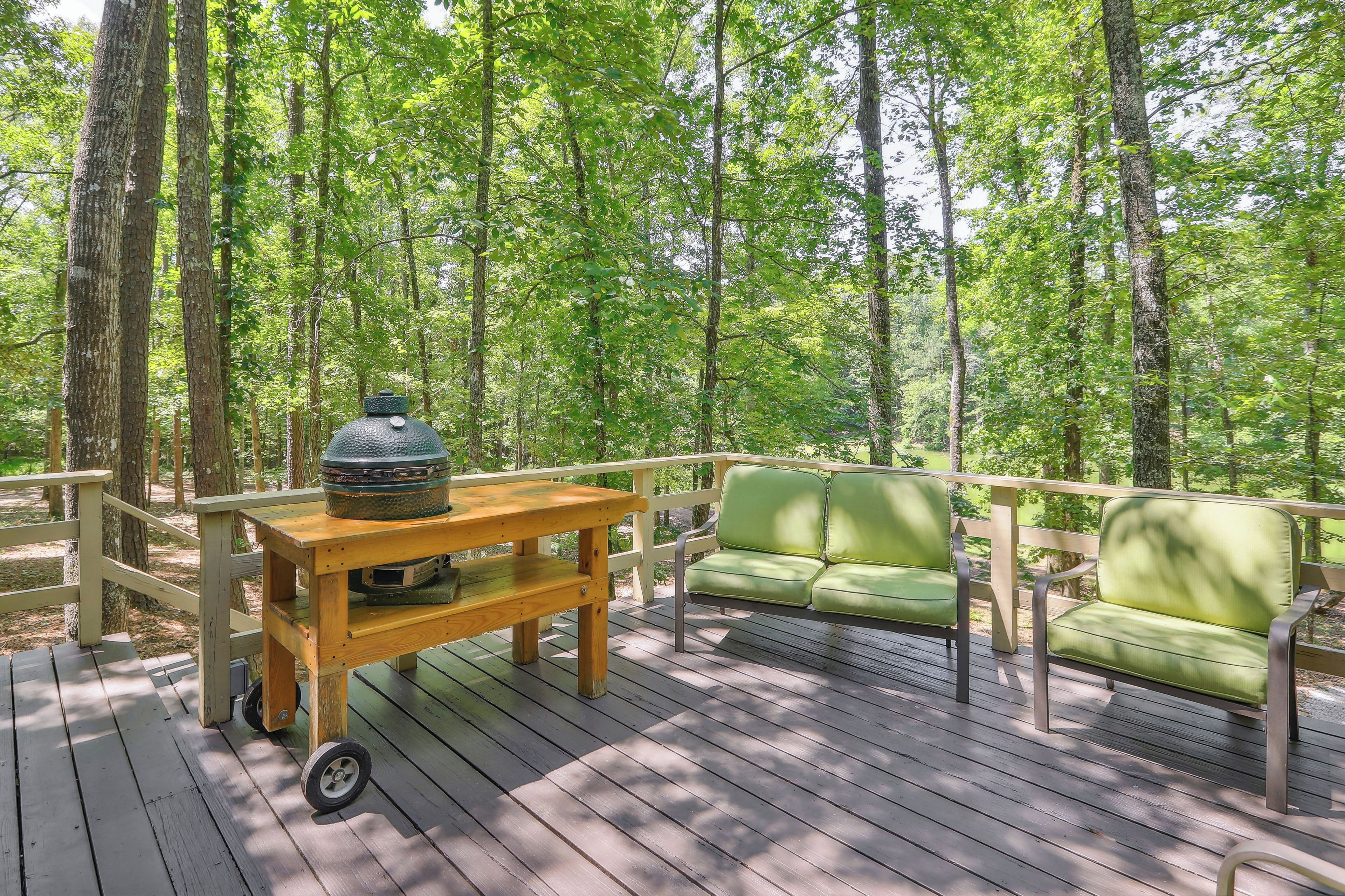 A wooden deck with a table and a green sofa, surrounded by tall trees.