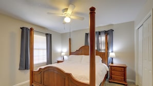 A four-poster bed with a wooden headboard, two bedside tables with lamps, and a ceiling fan. - 'the Ranger House' Columbus Home: Fenced Backyard (Columbus)