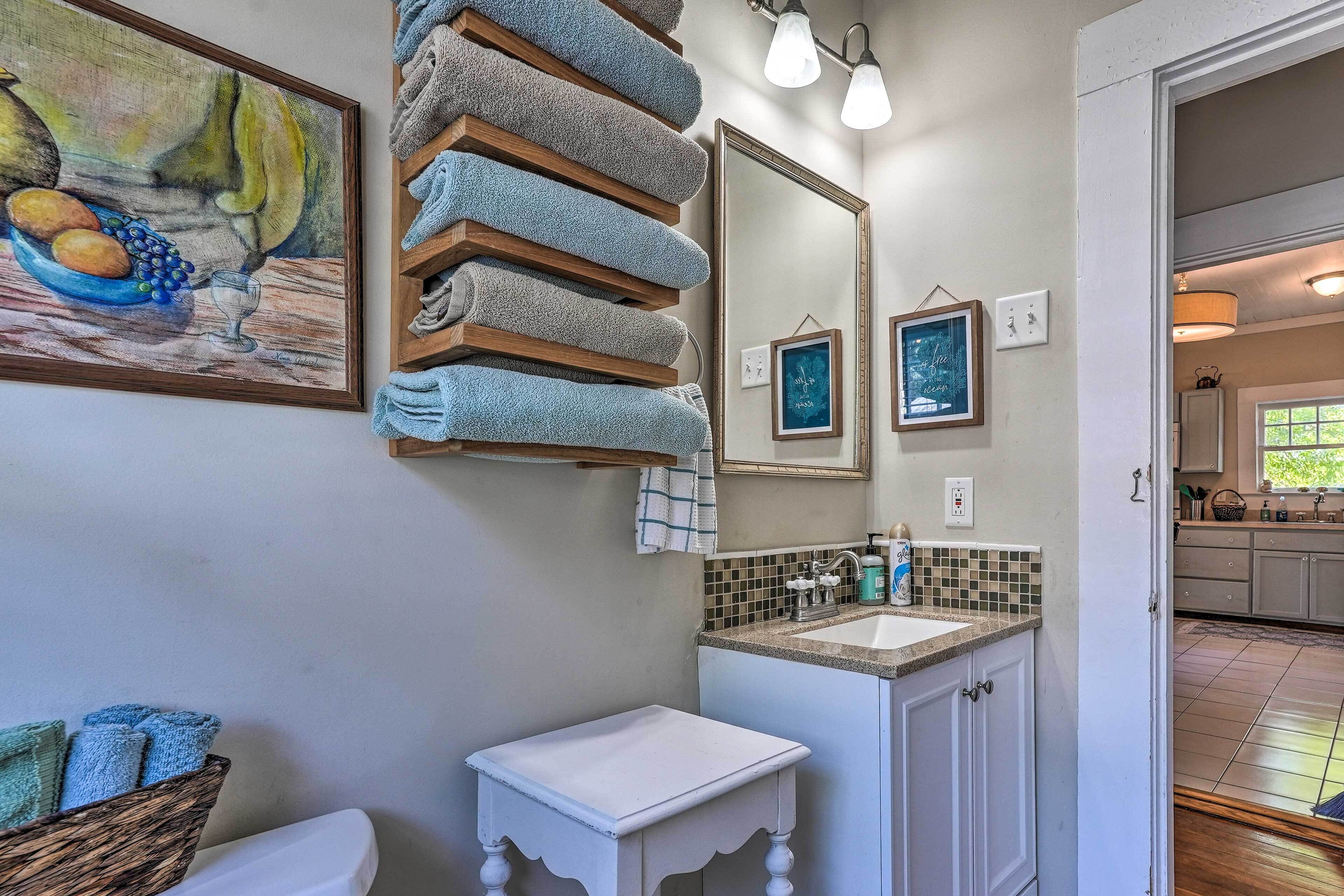 A bathroom with a sink, mirror, and towels stacked on a rack.