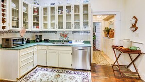 Una cocina con armarios blancos, microondas, cafetera y lavabo.