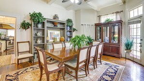 Comedor con una mesa y sillas de madera, rodeado de estantes con adornos y plantas.
