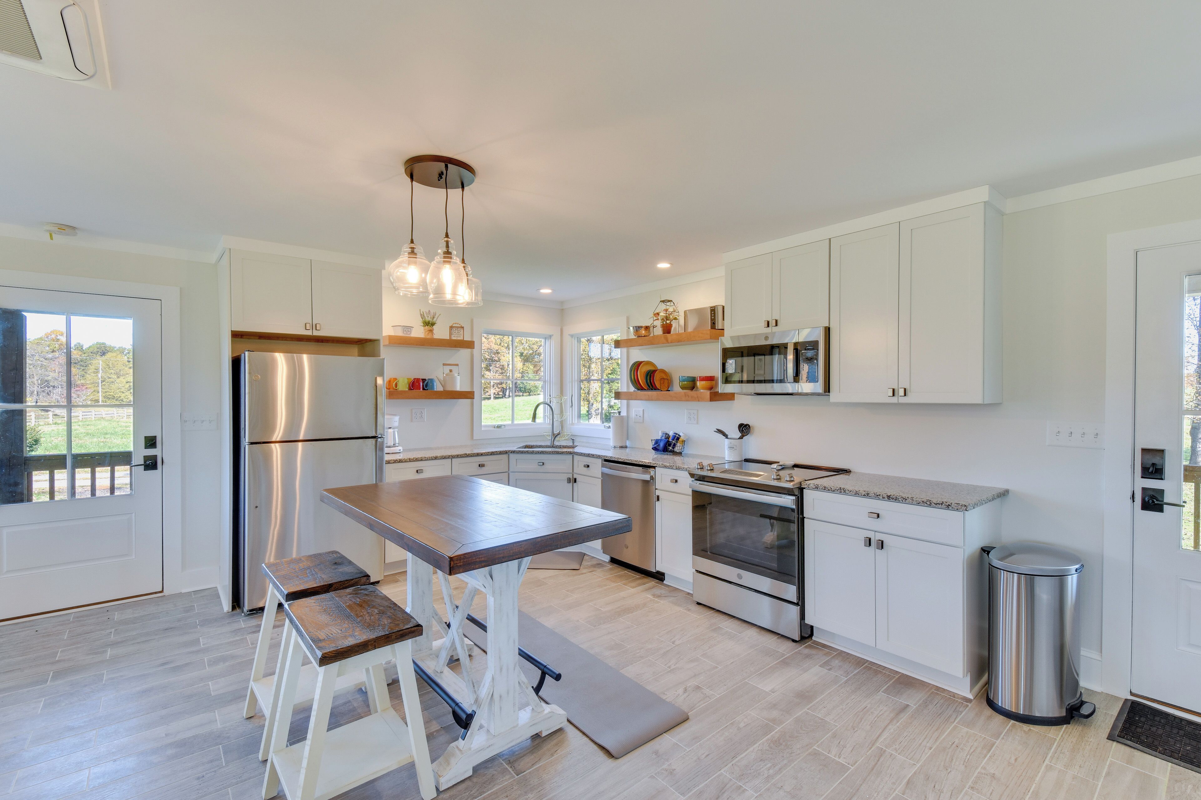 A modern kitchen with white cabinetry, stainless steel appliances, and a wooden island with stools.