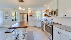 A modern kitchen with white cabinetry, stainless steel appliances, and a wooden island. - Modern Clarkesville Cottage w/ Decks & Patio! (Clarkesville)