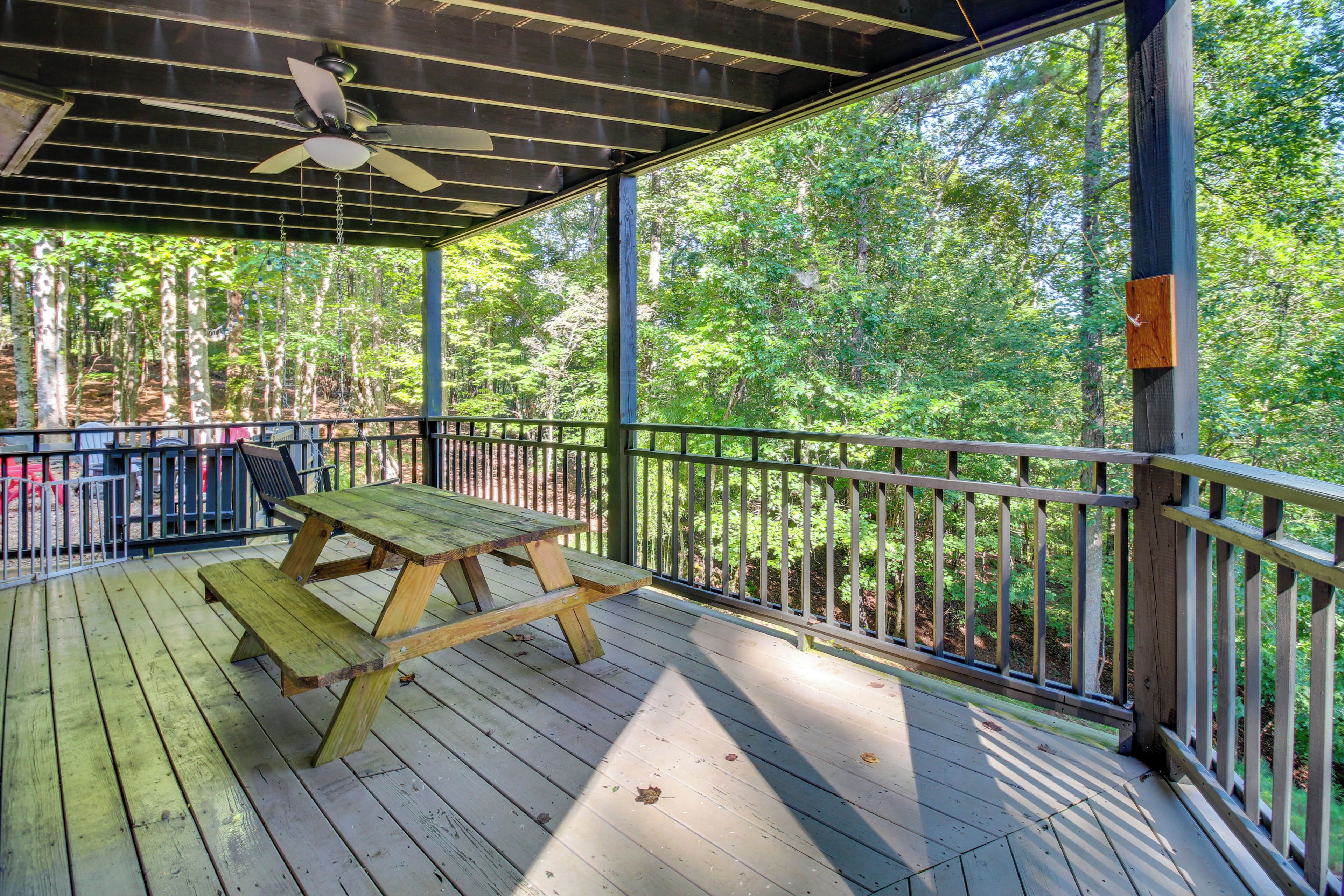 A wooden deck with a picnic table and a ceiling fan.