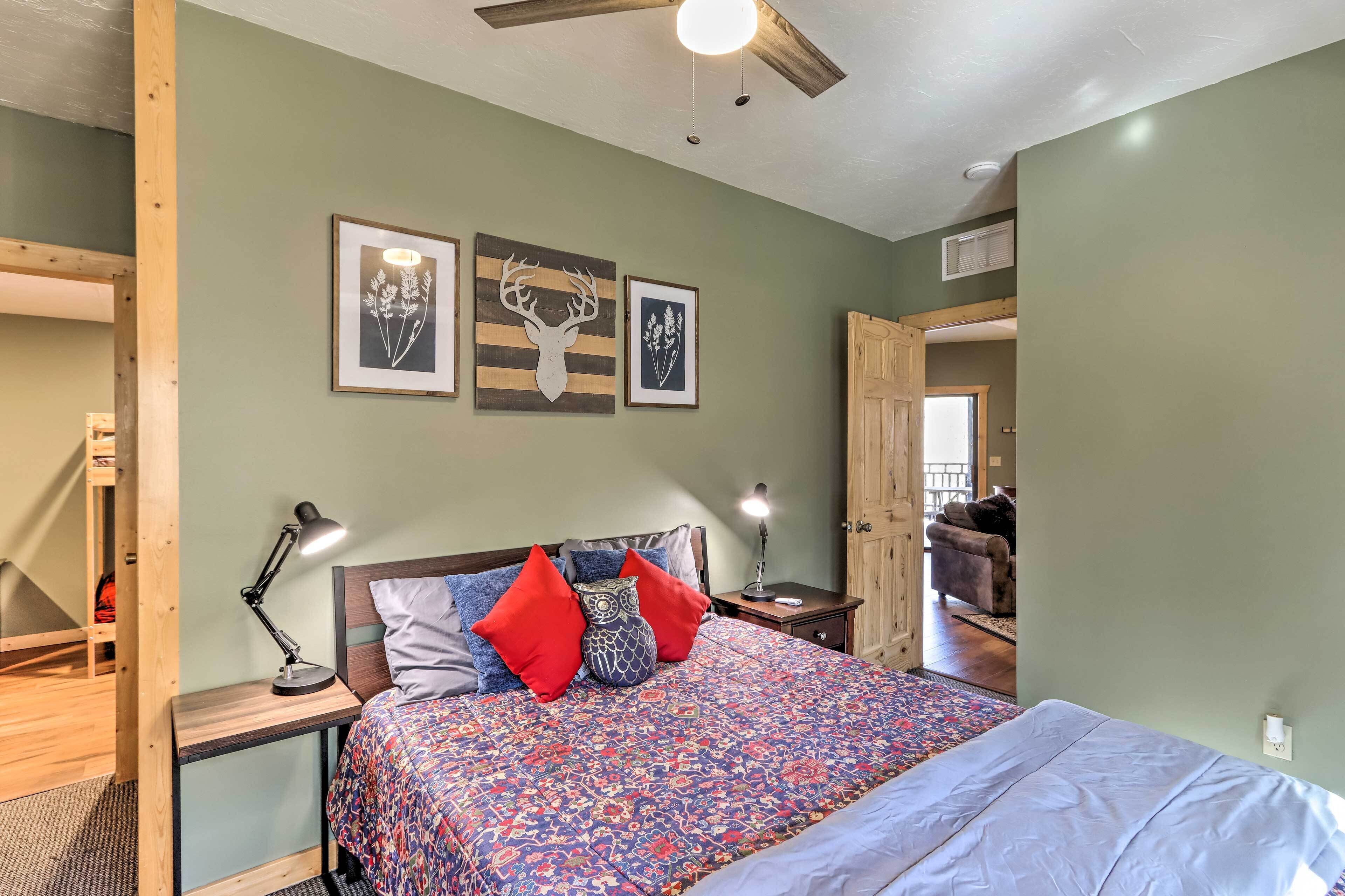A bedroom with a bed, two bedside tables, a ceiling fan, and framed wall art.