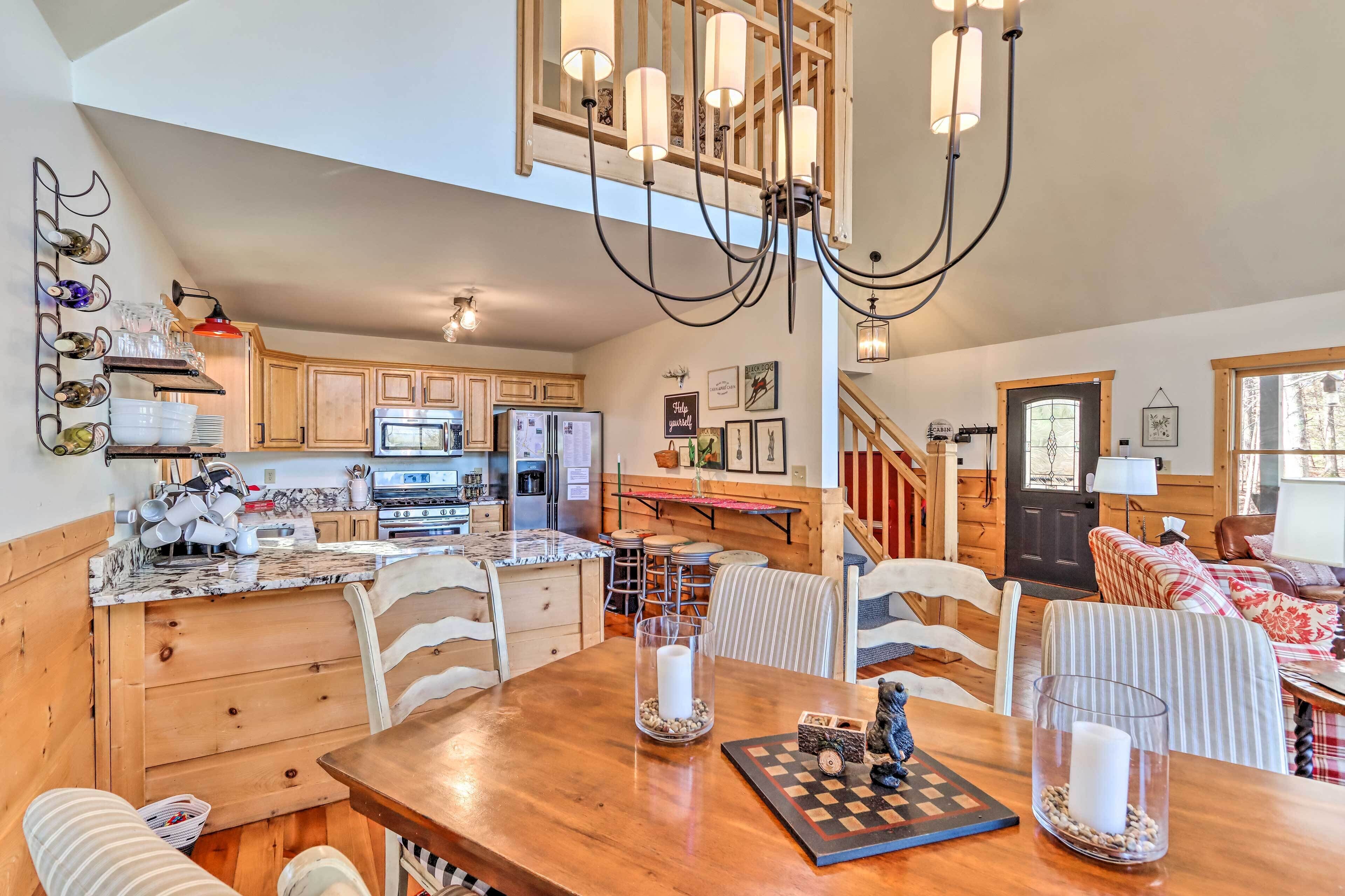A spacious kitchen with wooden cabinets, a dining area with a wooden table, and a staircase leading to a loft bedroom.