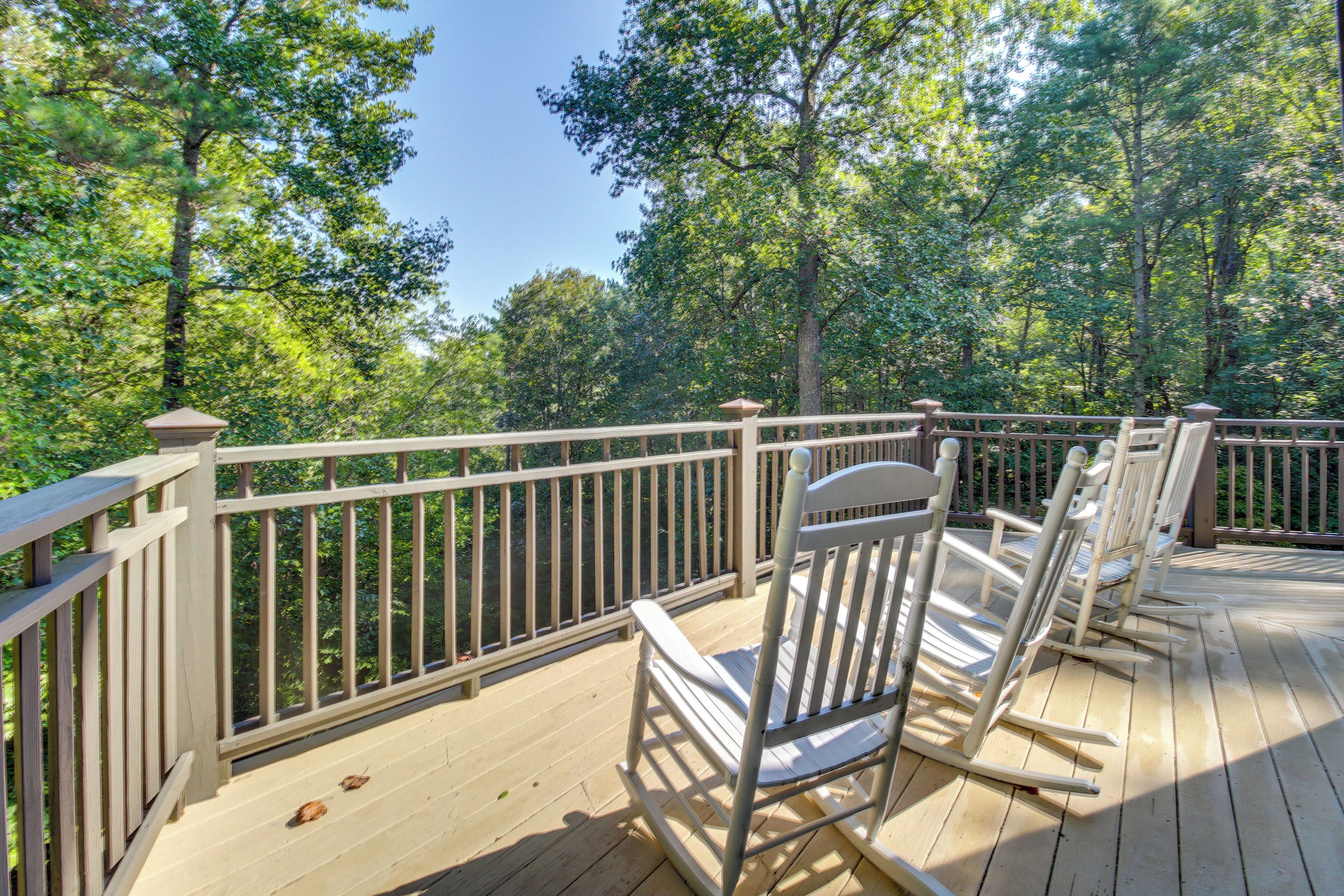 A wooden deck with a railing, surrounded by trees.