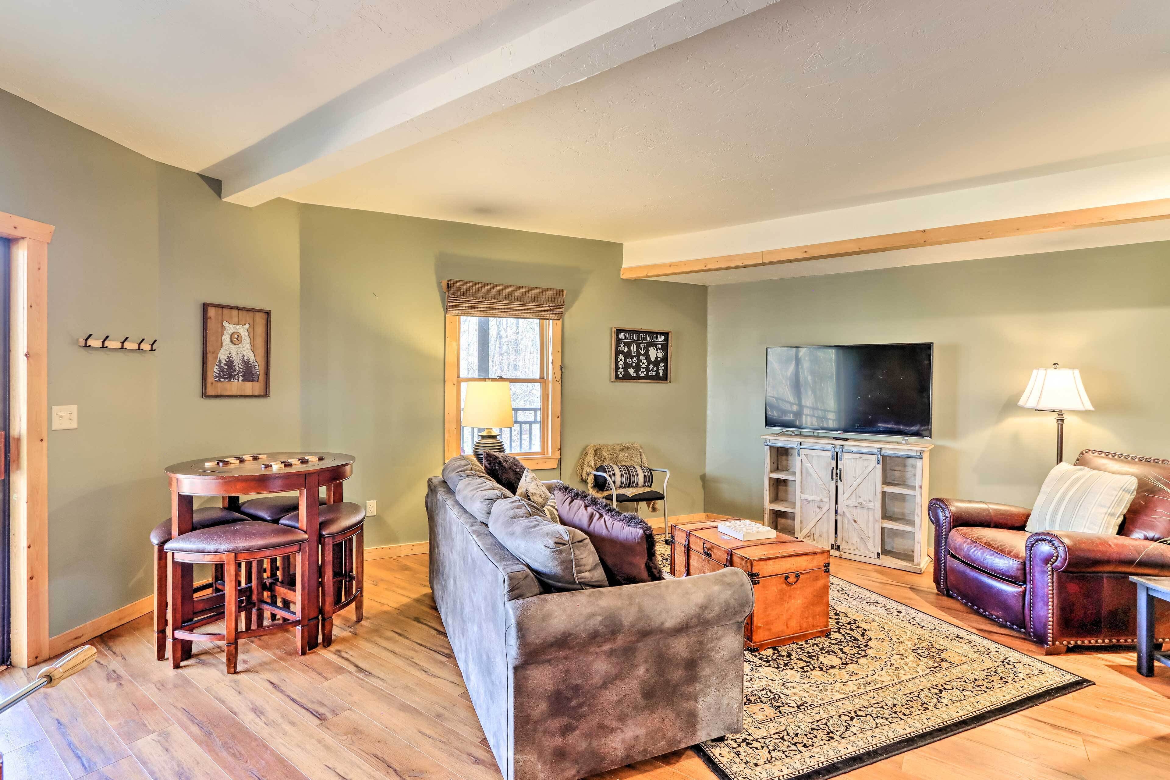 A living room with a sofa, two chairs, a coffee table, a TV, and a lamp.