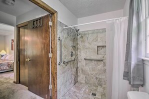 Een badkamer met een douche, toilet en een houten deur.