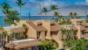 A resort with multiple buildings, palm trees, and a view of the ocean and mountains. - June Specials! Beautiful Stylish Condo W/ Amazing Ocean Views! (Kihei)