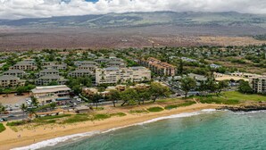 A coastal resort with multiple buildings, a beach, and a mountainous backdrop. - June Specials! Beautiful Stylish Condo W/ Amazing Ocean Views! (Kihei)